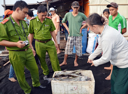 Chị Trịnh Thị Tùng, người chứng kiến vụ cá chết ở bè anh Dương Văn Thanh cung cấp thông tin cho cán bộ Phòng Cảnh sát môi trường (Công an tỉnh) về vụ việc cá bớp nuôi trên sông Chà Và chết hàng loạt chiều 25-12. Ảnh: GIA AN