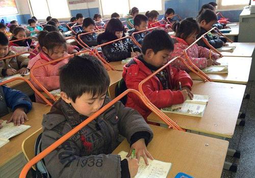 Một trường tiểu học ở Trung Quốc quyết định lắp khung thép cho bàn học để học sinh ngồi đúng tư thế và phòng tránh cận thị học đường.