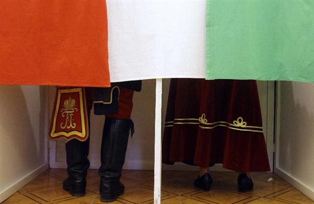Một người đàn ông mặc đồng phục truyền thống của Hungary thế kỷ 19 và một phụ nữ trong trang phục truyền thống trong quá trình bỏ phiếu trong một phòng phiếu ở Izaszeg, Hungary