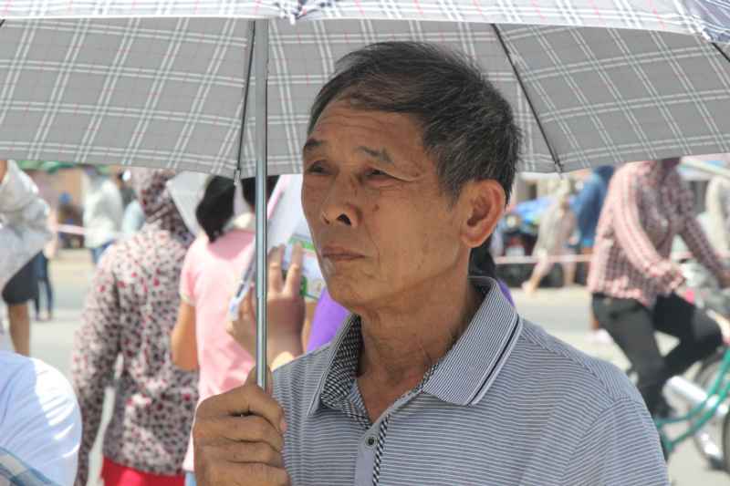 Một người bố tóc điểm sương đứng đợi con giữa trời nắng