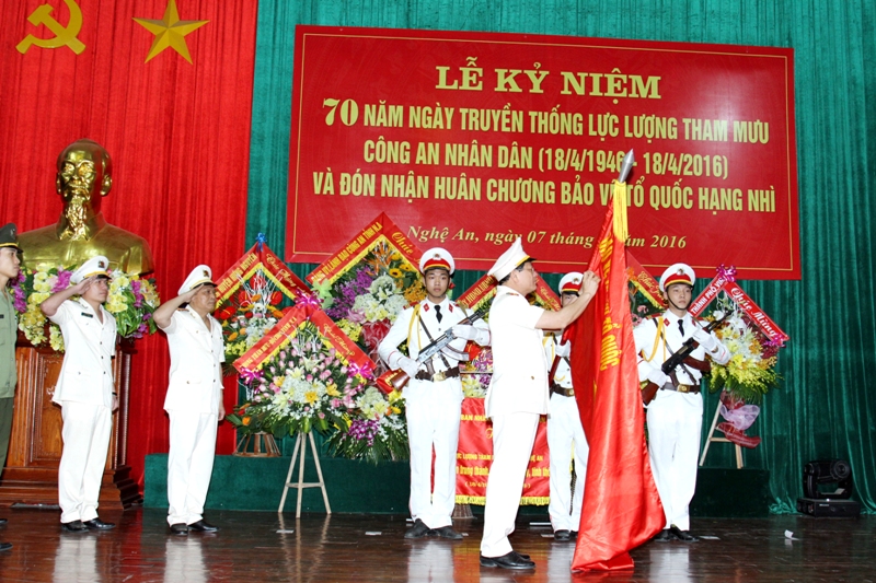 Thừa ủy quyền của Chủ tịch nước, Đại tá Nguyễn Hữu Cầu, Ủy viên BTV Tỉnh ủy, Giám đốc Công an tỉnh gắn Huân chương Bảo vệ Tổ quốc hạng Nhì lên lá cờ truyền thống của lực lượng Tham mưu Công an Nghệ An.
