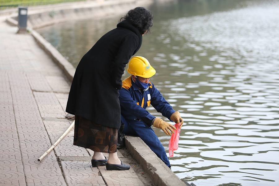 Công nhân vệ sinh giúp người dân thả cá nhẹ nhàng