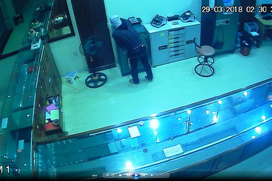 Camera an ninh ghi lại hình ảnh tên trộm cao lớn, chân đi khập khiễng, mặt bịt kín, đang lúi húi lấy vàng, bạc vào túi.