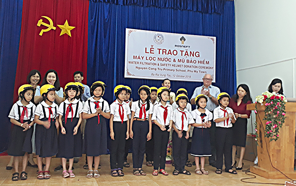 Đại diện Công ty Dầu khí Rosneft Vietnam tặng mũ bảo hiểm cho HS Trường TH Nguyễn Công Trứ.