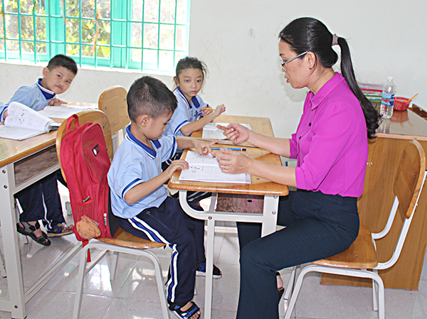 Giáo viên Trường Nuôi dạy trẻ khuyết tật (TP.Bà Rịa) tranh thủ giờ sinh hoạt để hỗ trợ các HS khuyết tật học yếu.  Ảnh: HOÀNG HƯỜNG