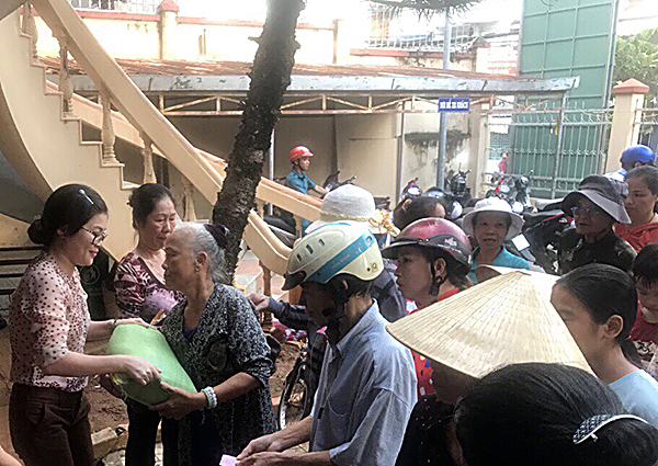 Chị Vũ Thị Minh Hạnh (bìa trái) tặng quà của Hội LHPN phường 5 cho người nghèo tại phường.