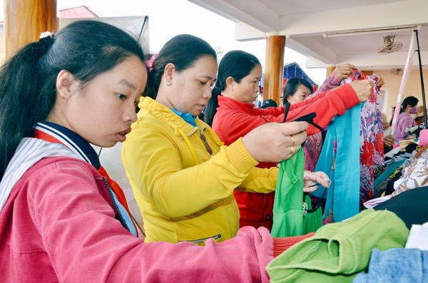 Học sinh và người dân xã Long Tân lựa quần áo tại gian hàng quần áo cũ.