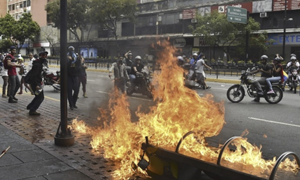 Người biểu tình đốt xe khi đụng độ với lực lượng an ninh tại Caracas ngày 23-1.