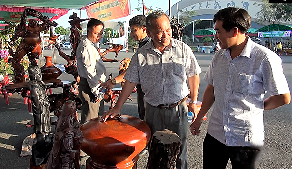 Ông Nguyễn Văn Thu (bìa phải), Trưởng Phòng VHTT huyện nghe nghệ nhân tư vấn các mặt hàng làm từ gỗ.
