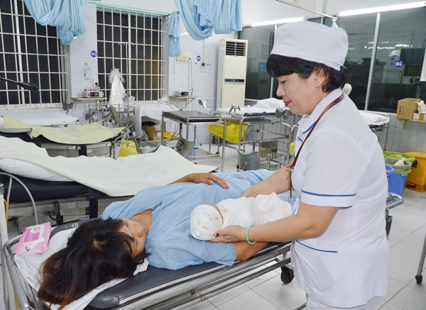Nữ hộ sinh hướng dẫn sản phụ chăm sóc trẻ sơ sinh tại Bệnh viện Lê Lợi sáng 8-2 (mùng 4 Tết). Ảnh: MINH NHÂN