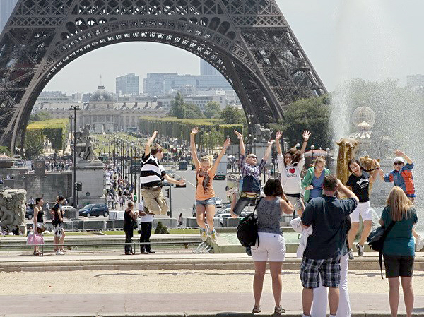 Khách du lịch bên Tháp Eiffel ở Paris (Pháp). Ảnh: AFP