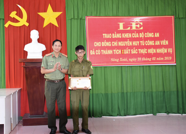 Đại tá Bùi Quang Chi, Phó Cục trưởng Cục V05 (Bộ Công an)  trao  Bằng khen của Bộ trưởng Bộ Công an đến anh Nguyễn Huy Tú.  Ảnh: Công Hoan.