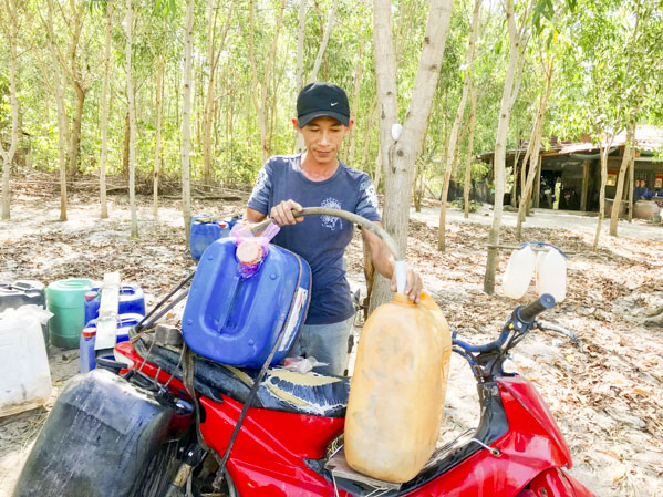 Anh Ngô Văn Tươi (tổ 1, thôn 9, xã Long Sơn) mua nước sạch đóng can để sử dụng.