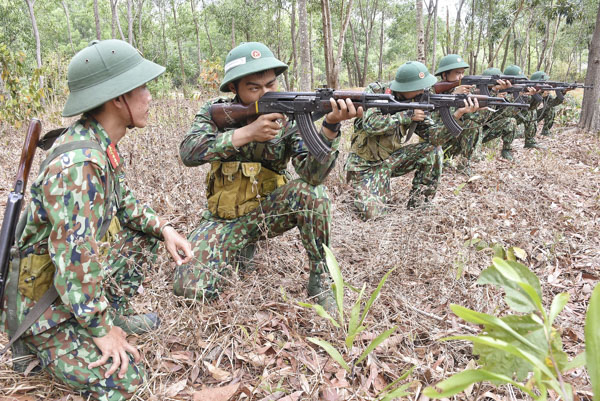 Cán bộ huấn luyện hướng dẫn chiến sĩ mới động tác ngắm bắn súng AK 47.