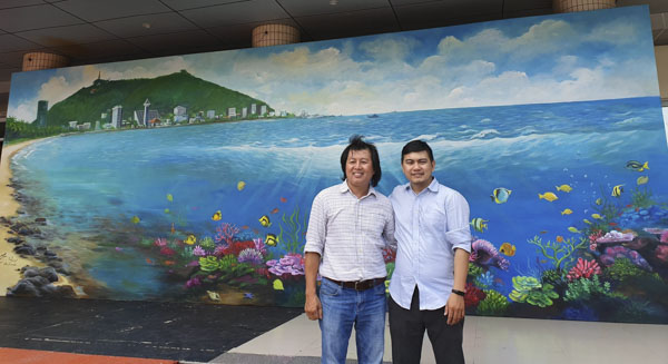 Họa sĩ Nông Cao Thanh (trái) cùng anh Lê Nguyễn Thiện Ân, Phó Giám đốc Công ty TNHH Toàn Hồng Ân bên bức tranh “Biển Bãi Trước Vũng Tàu”.