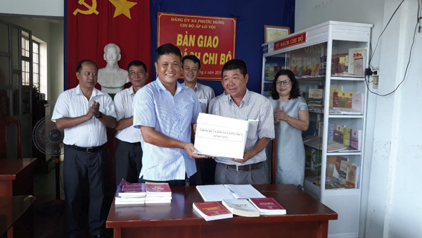 Ông Trần Thanh Thái, đại diện Chi bộ Du lịch (phải) trao sách cho đại diện Chi bộ ấp Lò Vôi.