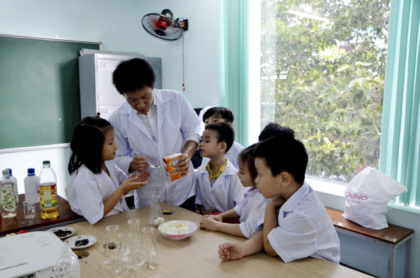 Thầy Trần Văn Phong hướng dẫn các em nhỏ (6-8 tuổi) thực hành cho trứng vào chai miệng nhỏ.