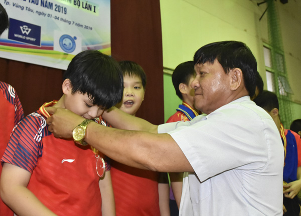 Ông Đặgn Văn Cường, đại diện Ban tổ chức trao huy chương cho các VĐV đoạt giải cao đồng đội nam nhóm tuổi 7-9.