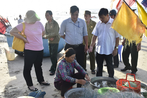Ông Nguyễn Văn Tài (bìa phải), Chủ tịch UBND phường 10 và các lực lượng yêu cầu một hộ ngư dân thu dọn việc bày bán hải sản trên bãi biển.