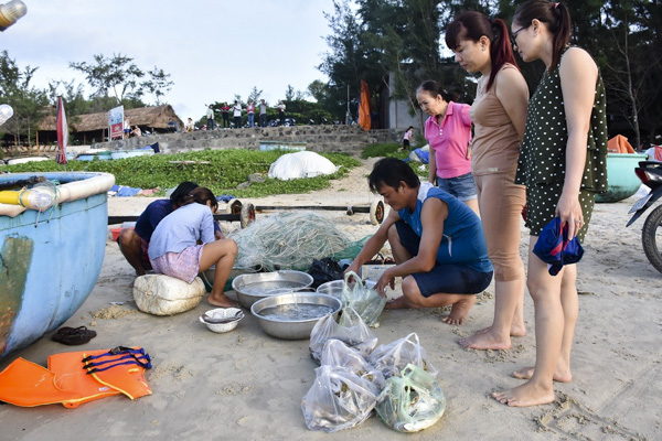 Người dân và du khách mua hải sản do ngư dân bày bán trên bãi biển.