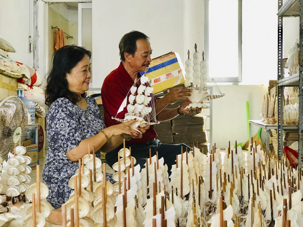 Ông Nguyễn Quang Hải và bà Vũ Thị Chức, chủ cơ sở sản xuất sò ốc mỹ nghệ Thanh Thêm bên các sản phẩm thuyền buồm được làm từ sò ốc.
