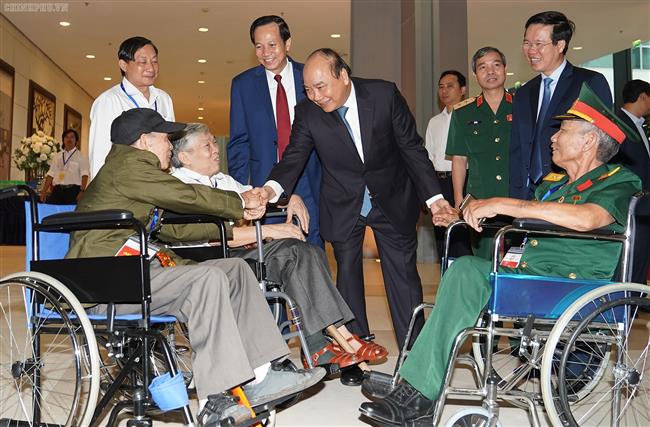 Thủ tướng thăm hỏi các đồng chí thương binh nặng tới dự buổi gặp mặt. Ảnh: VGP/Quang Hiếu