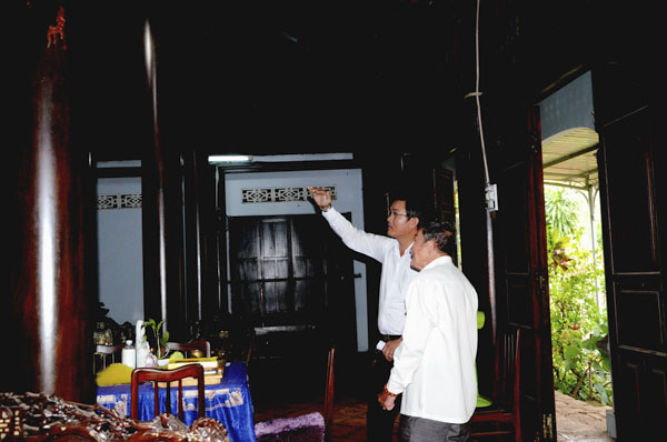 Ông Huỳnh Hữu Nghĩa (bên phải) giới thiệu lịch sử ngôi nhà cho khách đến tham quan.
