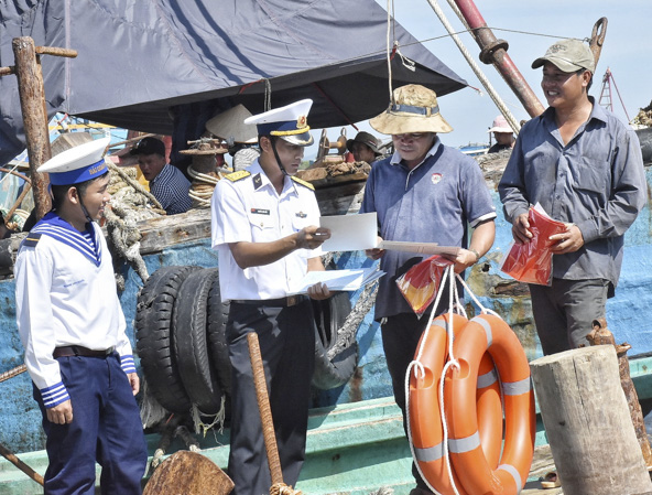 Cán bộ, chiến sĩ Vùng 2 Hải quân phát tờ rơi tuyên truyền về biển, đảo cho ngư dân xã Phước Hưng, huyện Long Điền.