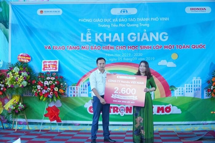 Đại diện Honda Đức Phát trao biển tặng mũ bảo hiểm tượng trưng cho hiệu trưởng nhà trường