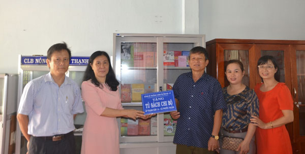 Bà Ngô Thị Liên (thứ hai từ trái qua), Hiệu trưởng Trường Chính trị trao tủ sách cho Chi bộ ấp Thạnh Sơn 1.
