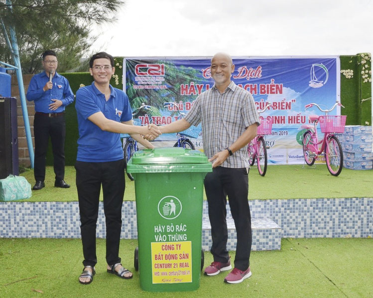 Ông Trầm Khương Minh (bìa phải), Giám đốc Công ty Bất động sản Century 21 Real trao thùng đựng rác cho anh Đỗ Minh Tân, Bí thư Huyện Đoàn Long Điền.