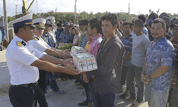 Cán bộ Trung tâm Hậu cần-Kỹ thuật đảo Sinh Tồn tặng quà cho các ngư dân gặp nạn trước khi lên tàu KN 410 về đất liền.
