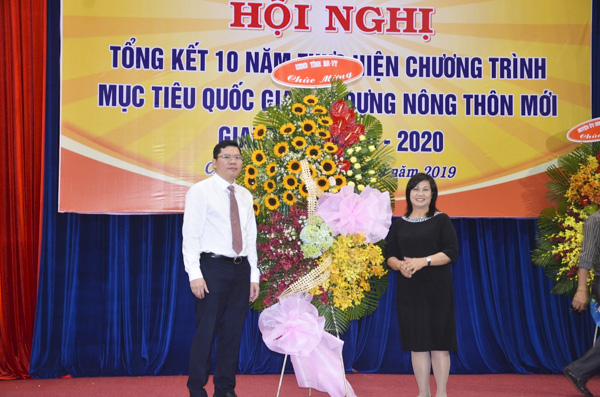 Ông Hoàng Nguyên Dinh (bên trái), Chủ tịch UBND huyện Châu Đức nhận lẵng hoa chúc mừng của UBND tỉnh BR-VT tại hội nghị tổng kết 10 năm thực hiện Chương trình mục tiêu Quốc gia xây dựng NTM.