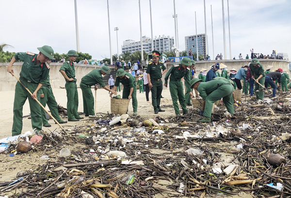 Lực lượng vũ trang hỗ trợ thu gom rác tại bãi tắm Thùy Vân. 