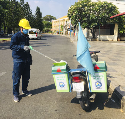 Công nhân sử dụng xe gắn máy để thu gom rác  trên đường phố.
