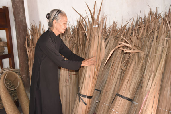 Dì Ba Kiềm sắp xếp lại những bó lá dừa nước dùng để tặng cho các gia đình có người thân qua đời.