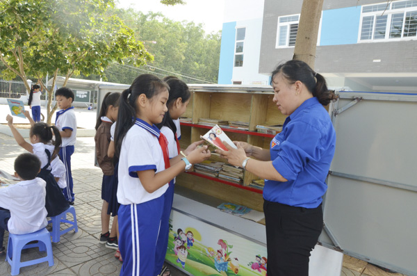 Cô Lê Thị Thúy Hồng, giáo viên Tổng phụ trách Đội Trường TH Văn Lang (TX.Phú Mỹ) trao sách từ “Tủ sách sân trường”  đến các em HS. Ảnh: MINH MINH