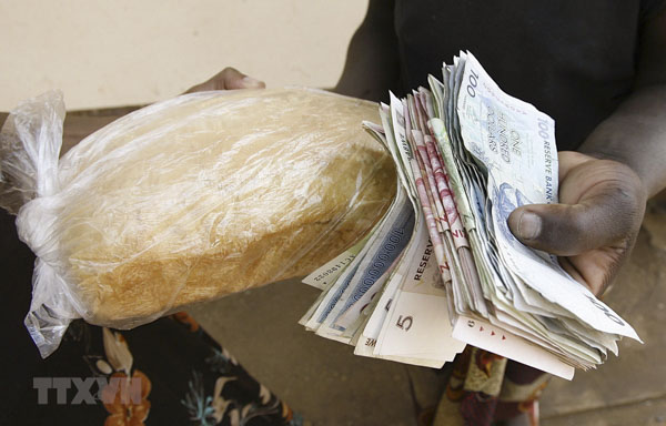 Người dân trả tiền để mua bánh mì  tại Harare, Zimbabwe. (Ảnh: AFP)