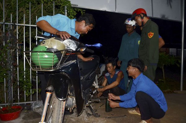  Anh Nguyễn Văn Duân (ngồi thứ hai từ phải qua) đang kiểm tra xe cho một thành viên của CLB Thanh niên xung kích.