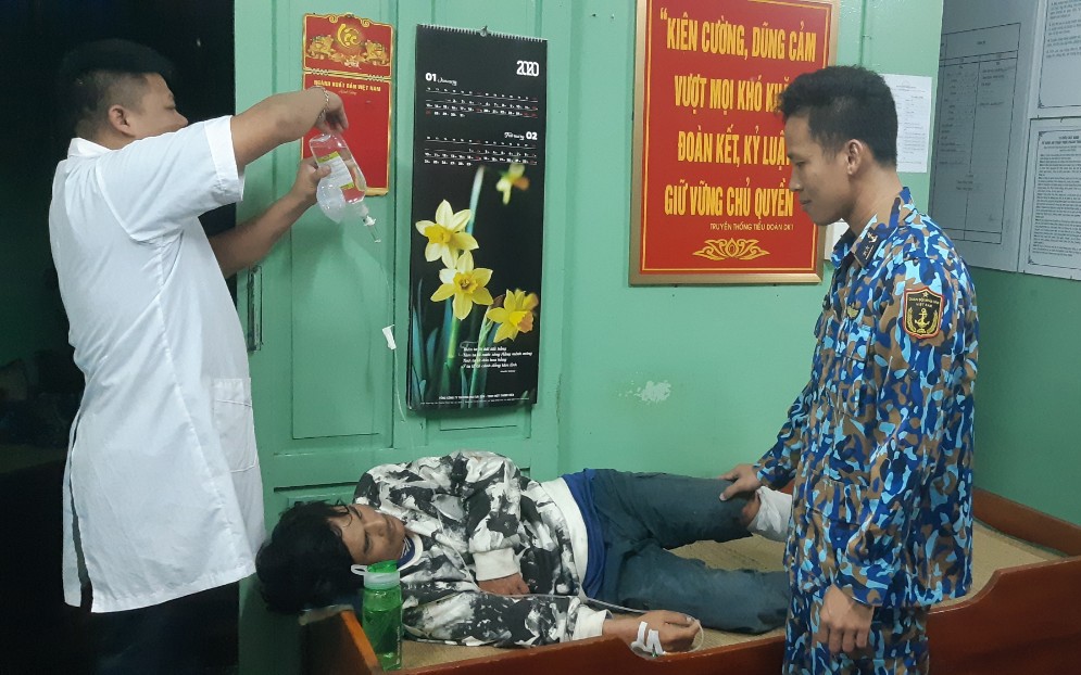 Chỉ huy và quân y nhà giàn chăm sóc bệnh nhân Trần Văn Mên sau khi khâu 8 mũi vết thương cẳng chân trái. 