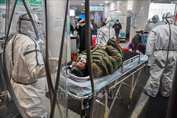 Nhân viên y tế chuyển bệnh nhân nhiễm virut corona gây viêm phổi tới Bệnh viện Chữ Thập đỏ ở thành phố Vũ Hán, tỉnh Hồ Bắc, Trung Quốc ngày 25/1/2020. Ảnh: AFP/TTXVN
