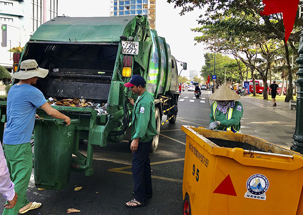 Công nhân Công ty VESCO thu gom rác lên xe chuyên dụng trên đường Thùy Vân sáng mùng 3 Tết.