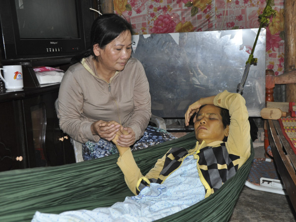 Chị Phan Thị Mỹ Phượng chăm sóc em gái đang bị cơn đau do bệnh tật hành hạ.