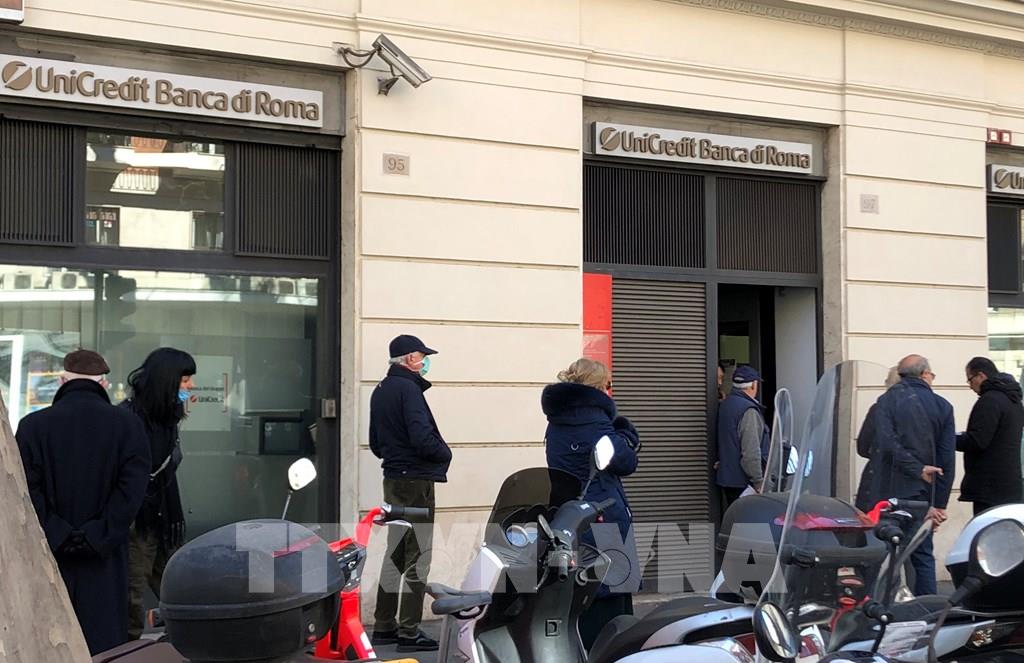 Người dân xếp hàng bên ngoài một ngân hàng ở Rome ngày 10/3/2020, trong bối cảnh Italy tiến hành phong tỏa toàn quốc nhằm đối phó dịch COVID-19 lan rộng. Ảnh: THX/TTXVN
