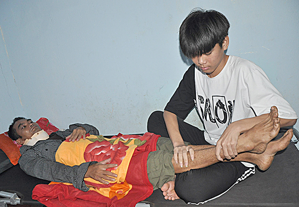 Em Nguyễn Lý Kỳ Nguyên bóp chân cho cha đỡ cơn đau do thương tật gây ra.