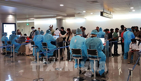 Nhân viên Trung tâm Kiểm dịch y tế quốc tế hướng dẫn hành khách thực hiện tờ khai y tế trước khi làm thủ tục nhập cảnh tại sân bay Tân Sơn Nhất TP.Hồ Chí Minh. (Ảnh: TTXVN)