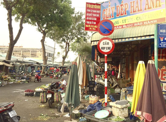 Bày bán hàng hóa ngay dưới bảng “Cấm họp chợ” tại khu vực chợ Ngãi Giao (ảnh chụp ngày 24/3).