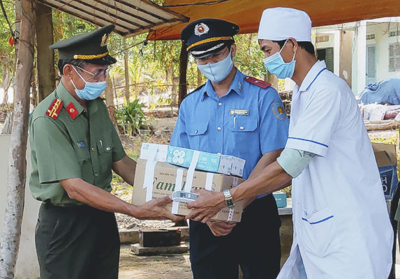 Đại tá Bùi Văn Thảo (bìa trái), Giám đốc Công an tỉnh trao các trang thiết bị, vật tư y tế cho tổ kiểm soát liên ngành đặt tại Quốc lộ 55.