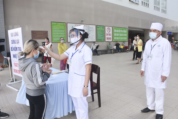Nhân viên y tế Bệnh viện Bà Rịa kiểm tra thân nhiệt để sàng lọc người vào bệnh viện.