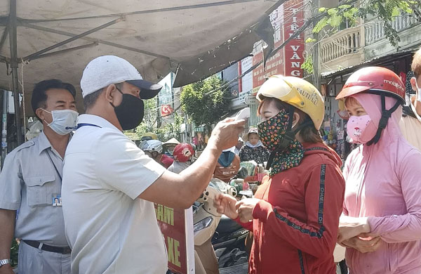 Nhân viên Ban Quản lý chợ Rạch Dừa (TP. Vũng Tàu) đo thân nhiệt cho người đi chợ sáng 30/4.